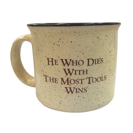 Coffee mug with 'He who dies with the most tools wins' message.